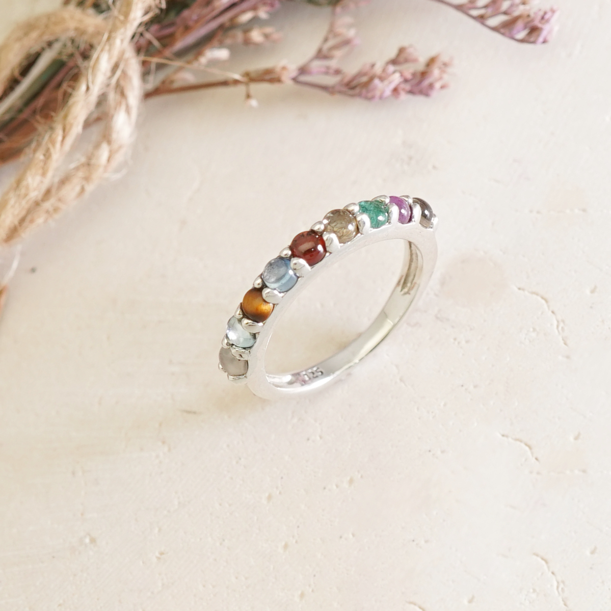 แหวนนพเก้า ตัวเรือนเงินแท้ เสริมมงคล ตัวเรือนเป็นเงินแท้ มาตรฐานสากล 92.5% ไม่ผสมโลหะหนัก ประดับด้วยพลอยแท้ 9 ชนิด เจียรแบบหลังเบี้ย เสริมสร้างความสิริมงคล