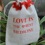 ถุงผ้ากระสอบ ถุงผ้าดิบ สำเร็จรูป พิมพ์ลาย ความหมาย รักคือยาที่ดีที่สุด แต่งโบว์สีแดง ถุงผ้าขนาด 10x15 cm 711461